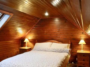 a bed in a wooden room with two lamps at Buckhood - Swwy in Pearsie