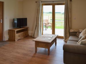 a living room with a tv and a couch and a table at Saddlers Cottage in Alkham