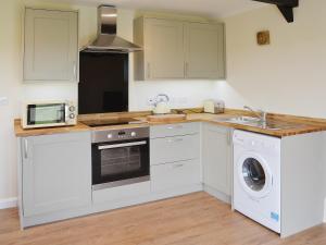 a kitchen with white cabinets and a washer and dryer at Saddlers Cottage in Alkham