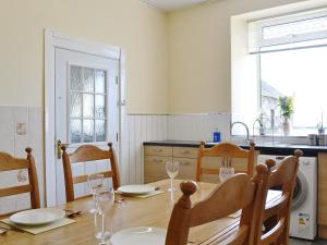 a dining room with a table and chairs and a kitchen at Old Barn Farmhouse in Uplawmoor