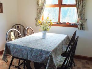 a dining room table with a vase of flowers on it at Olafs Cottage in Garlieston