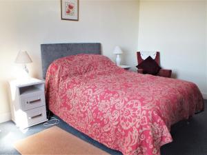a bedroom with a bed with a red bedspread at Olafs Cottage in Garlieston