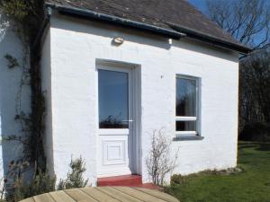 a white house with a door and windows at Olafs Cottage in Garlieston