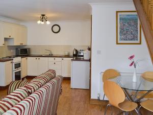 cocina con armarios blancos, mesa y sillas en Fawnlea Cottage en Staindrop