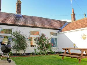 a white house with a picnic table and a bench at Little Tern in Winterton-on-Sea