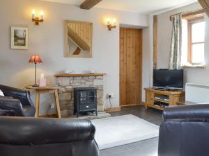 a living room with a fireplace and a television at Stocks Tree Cottage in Preston Wynne