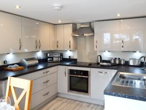 a kitchen with white cabinets and black counter tops at Booth Farm Bungalow in Hollinsclough
