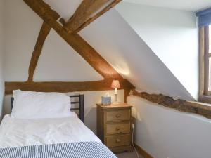 a bedroom with a bed and a table with a lamp at Stocks Tree Cottage in Preston Wynne