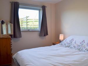 a bedroom with a white bed and a window at Booth Farm Bungalow in Hollinsclough