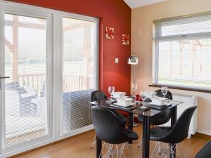 a dining room with a table and chairs and windows at Winston Lodge in Swinderby