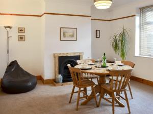 une salle à manger avec une table, des chaises et une cheminée dans l'établissement Holmlea, à Alnwick