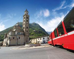 a red train traveling past a building with a clock tower at Casa Giuliana in Teglio