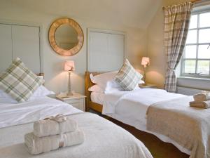 twee bedden in een kamer met twee lampen en een spiegel bij Tickton Hall Cottage in Tickton