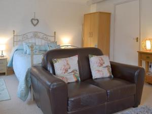 a brown leather chair in a bedroom with a bed at Kingfisher Apt - B4866 in Saint Cleer