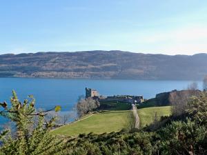 a castle on a hill next to a body of water at Burns Cottage in Drumnadrochit