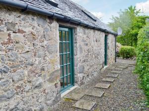 a stone building with a green door and stairs at Burns Cottage in Drumnadrochit