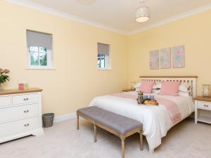 1 dormitorio con 1 cama grande con almohadas rosas en Graces Cottage en Port of Menteith