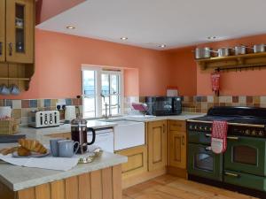 a kitchen with orange walls and a green oven at Graces Cottage in Port of Menteith