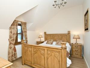1 dormitorio con cama de madera y ventana en Magnolia Cottage en Aberaeron