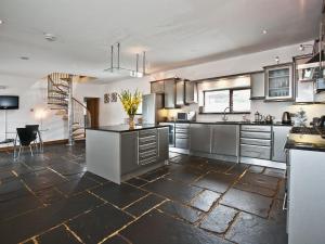 a large kitchen with stainless steel appliances and a staircase at The Cowshed in Froghall