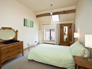a bedroom with a bed and a mirror and a dresser at The Cowshed in Froghall
