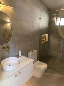 a bathroom with a toilet and a sink and a shower at Hilltop Woods Noosa in Tinbeerwah