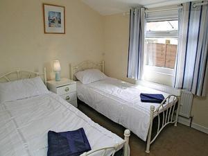 two beds in a small room with a window at Brecklands in Scratby