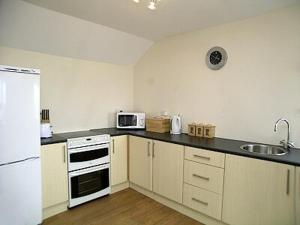 a kitchen with a white refrigerator and a sink at Brecklands in Scratby