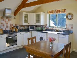 uma cozinha com armários brancos e uma mesa de madeira em The Roost em Blisland