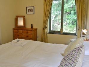 um quarto com uma cama branca e uma janela em The Roost em Blisland