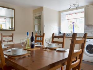 a dining room table with wine glasses and a kitchen at The Coach House in Greenodd