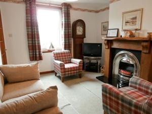 sala de estar con sofá y chimenea en 15 Cairnbaan Cottage, en Cairnbaan