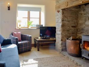 ein Wohnzimmer mit einem Steinkamin und einem TV in der Unterkunft Bryn Gwnog in Capel Garmon