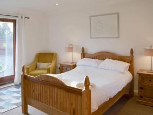 a bedroom with a bed and a chair and a window at Beech Barn in Horning