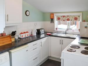 a kitchen with white cabinets and a counter top at Half Moon Cottage in Martham