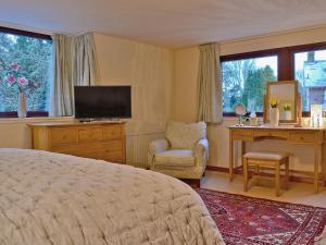 a bedroom with a bed and a desk and a television at The Gregorton Coachhouse in Rattray