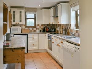 una cocina con armarios blancos y fregadero en Blackthorn Cottage en Norton Disney