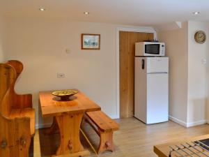 a kitchen with a table and a white refrigerator at The Old Haybarn in Long Sutton