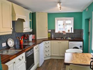 YoxfordにあるCoach House Cottageの白いキャビネットと緑の壁のキッチン