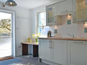 a kitchen with white cabinets and a large window at Loch Shore Cottage in Dornie