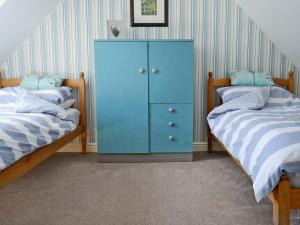 a blue cabinet in a bedroom with two beds at Loch Shore Cottage in Dornie