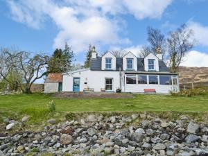 a white house on the side of a hill at Loch Shore Cottage in Dornie