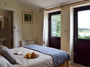 a bedroom with a bed with a plate of food on it at Hoppers Cottage in Ticehurst