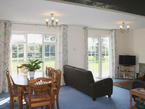 a living room with a table and chairs and a television at Jubilee Cottage in Pyworthy