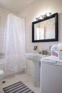 La salle de bains blanche est pourvue d'un lavabo et d'un miroir. dans l'établissement Captain's Quarters at Fiscardo Waterfront-feel the breeze, à Fiskardho