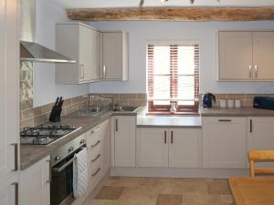 a kitchen with white cabinets and a stove top oven at The Cob Barn - Ukc1852 in Shaldon