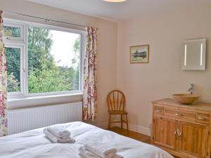 1 dormitorio con cama, ventana y silla en Kilnshaw, en Ambleside