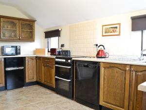 uma cozinha com armários de madeira e electrodomésticos pretos em The Coach House em Drybrook