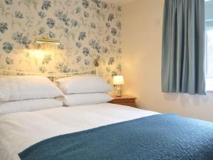 Drybrook的住宿－The Coach House，一间卧室配有一张带花卉壁纸的床