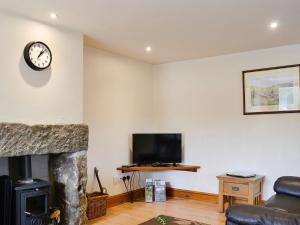 a living room with a fireplace and a tv at Mill Barn in Burnsall